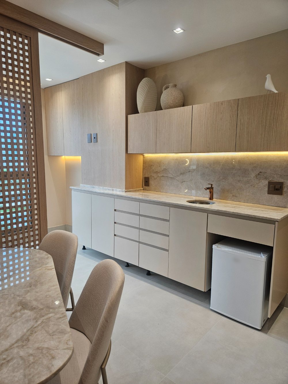 Sala de Ginecologia da Flèr, com marcenaria clara, bancada de mármore e mesa com cadeiras