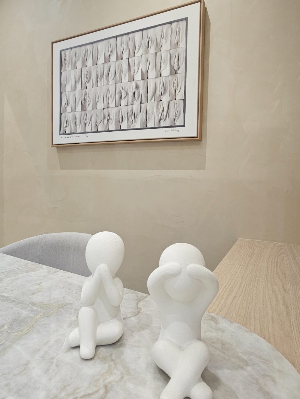 Esculturas brancas sobre a mesa de mármore da Flèr, com quadro ao fundo